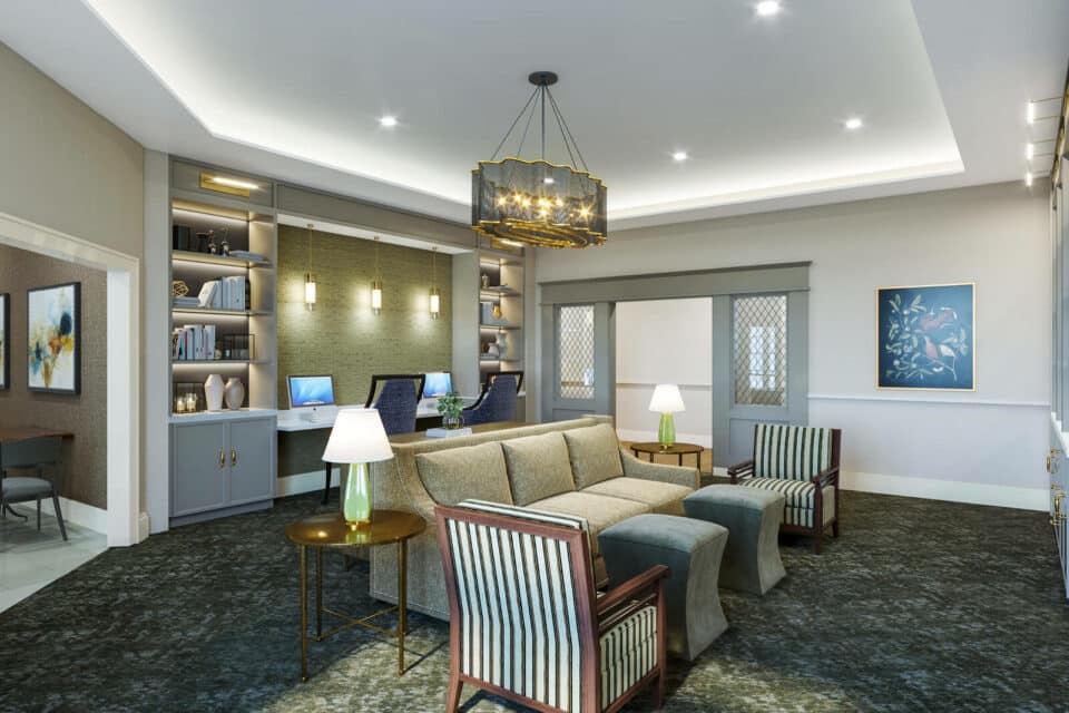 3D digital rendering of the library including bookshelves at back wall on each side of desk with two computers, couch and two chairs, two tables with lamps and striped sitting chairs with ottomans at center of room. and bronze/gold chandelier hanging above.