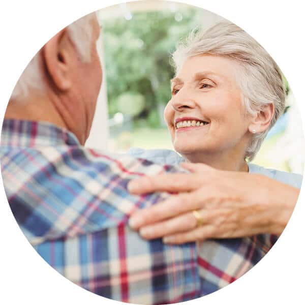 Senior couple embracing and smiling at each other.