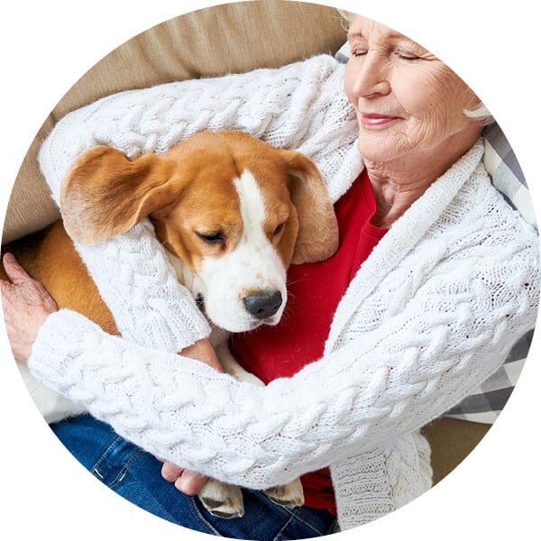 Senior woman snuggling with her dog on a sofa