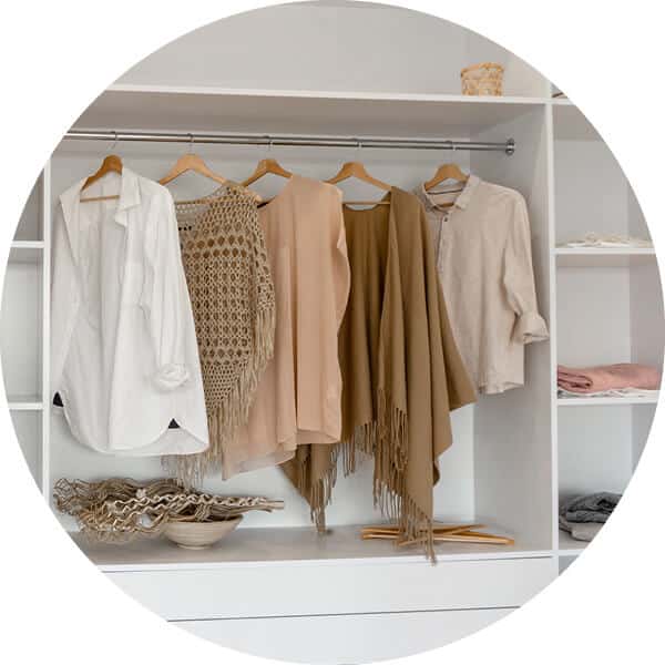 Close up view of woman's clothing hanging in a closet with white shelving.