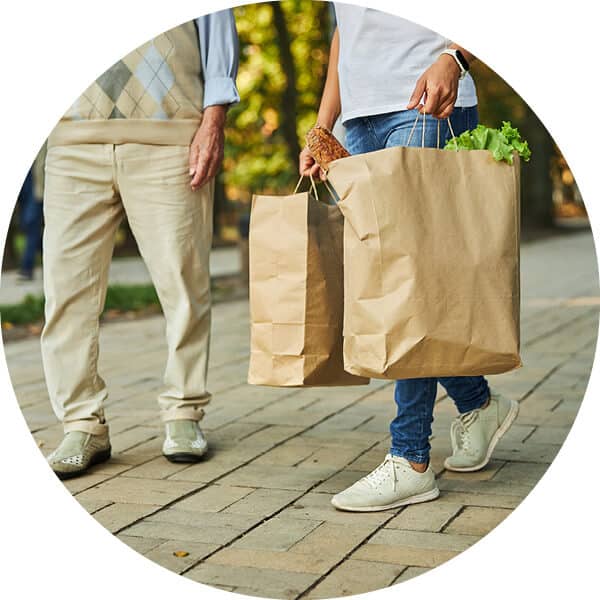Close up view of couple's legs and hands holding grocery shopping bags