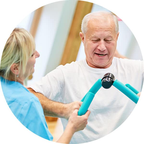 Senior man using exercise equipment with the assistance of caregiver.